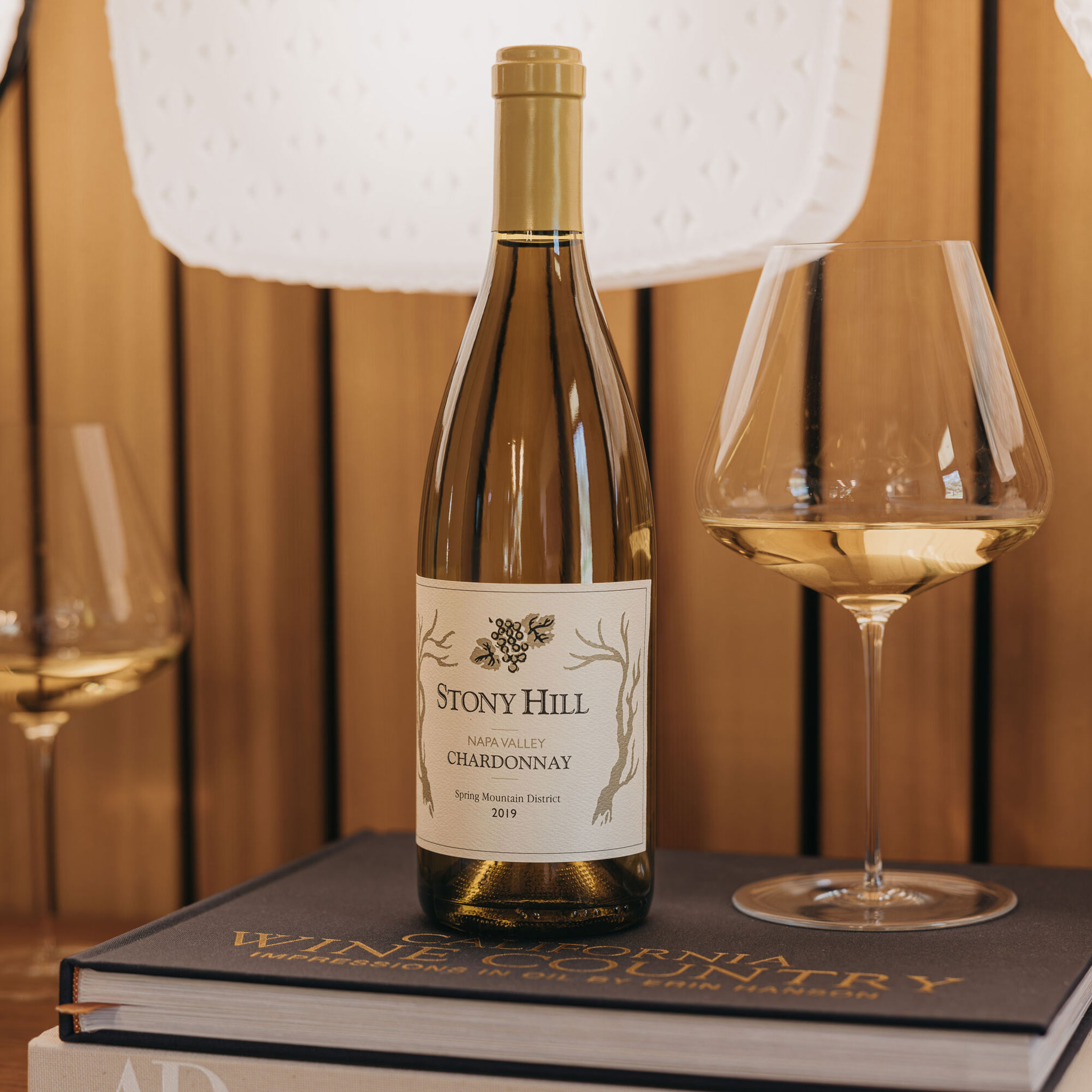 A bottle of 2019 Stony Hill Chardonnay on a stack of books, on top of a table.